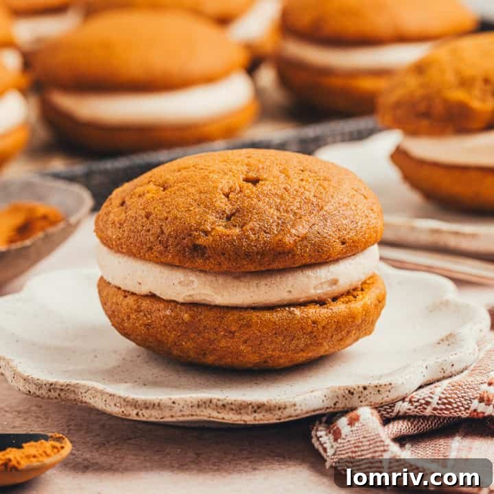 A perfectly assembled pumpkin whoopie pie with cinnamon cream cheese filling on a plate.