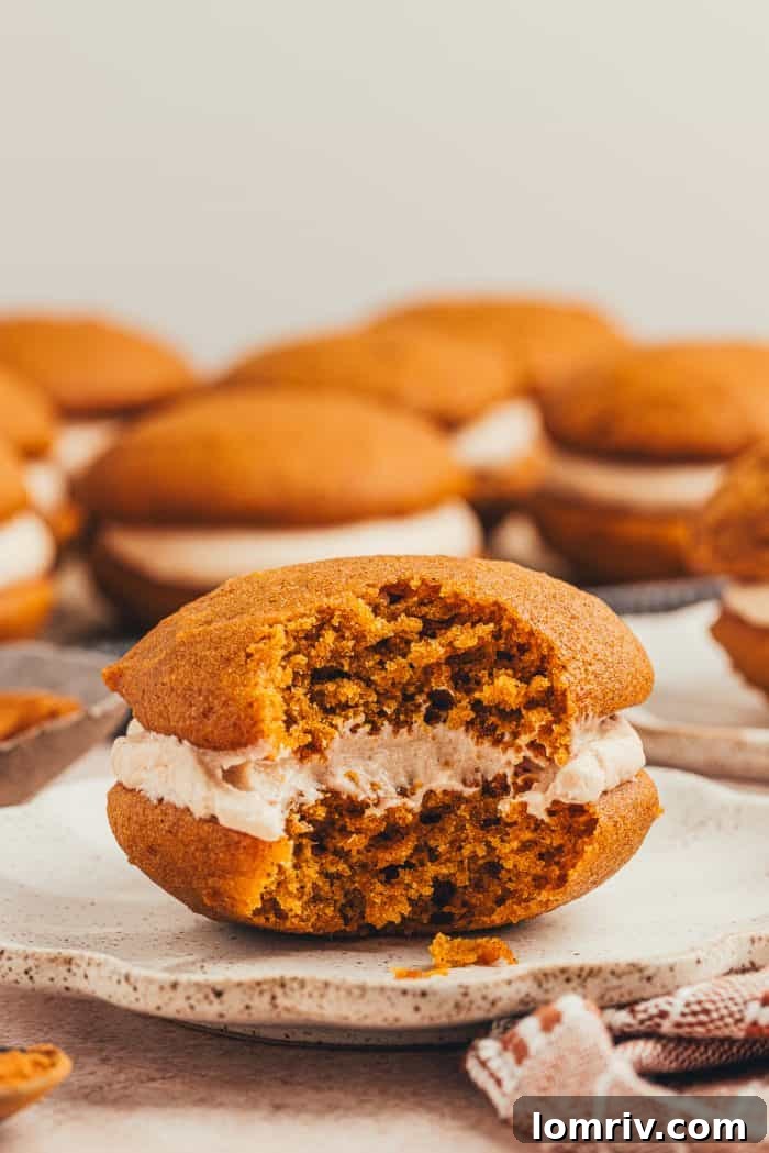 A single, delectable pumpkin spice whoopie pie with a bite missing, presented beautifully on a plate.