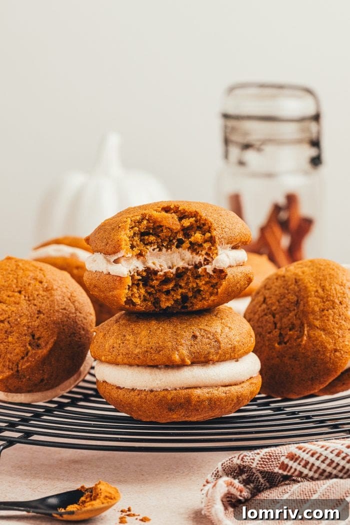 Freshly baked pumpkin whoopie pies cooling on a round wire rack, their perfectly domed tops visible.
