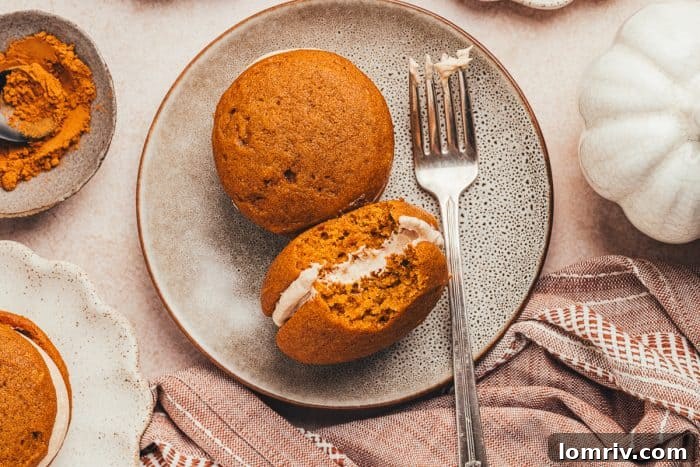 Two enticing whoopie pies on a plate, one with a delectable bite taken, accompanied by a fork.
