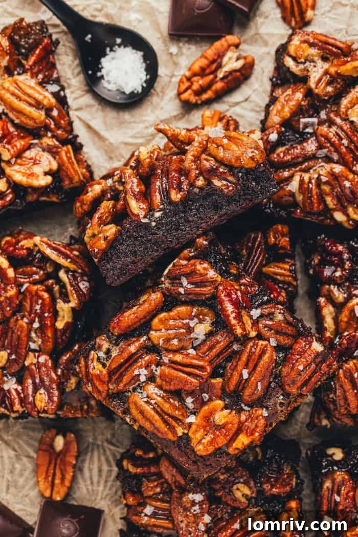 Various pecan pie brownies are scattered in a pile on parchment paper.
