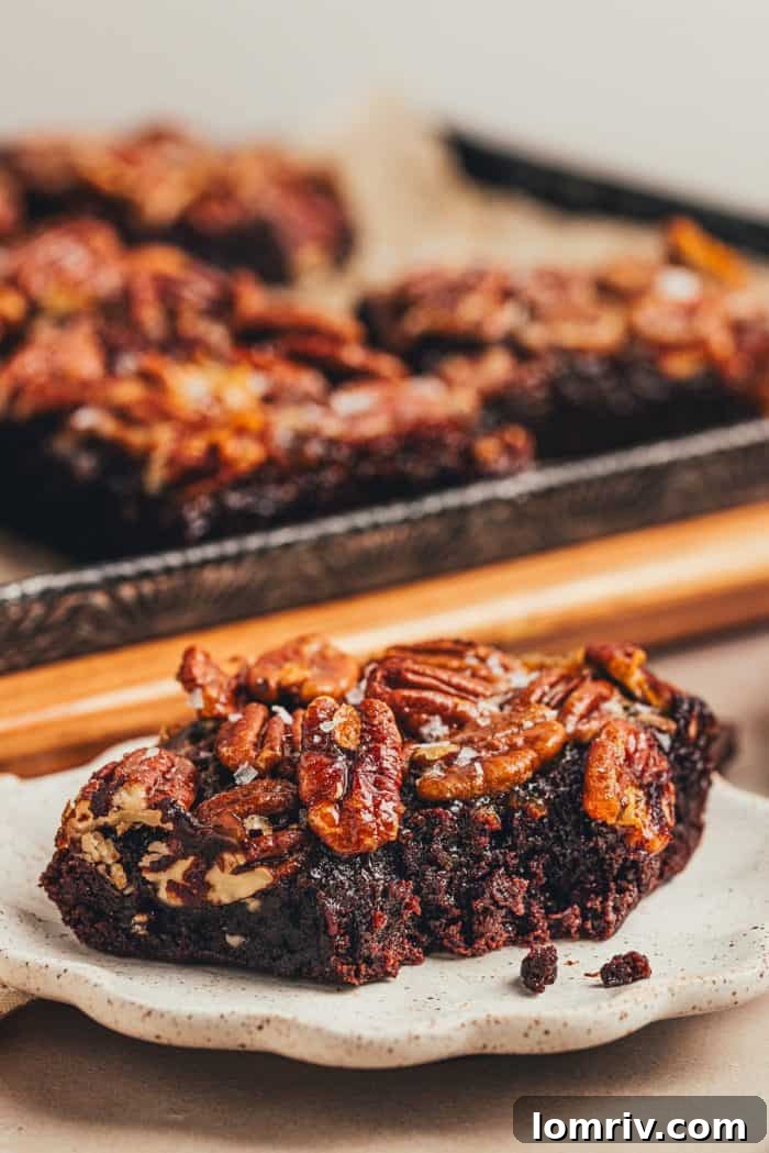 Two pecan pie brownies are on a white plate.