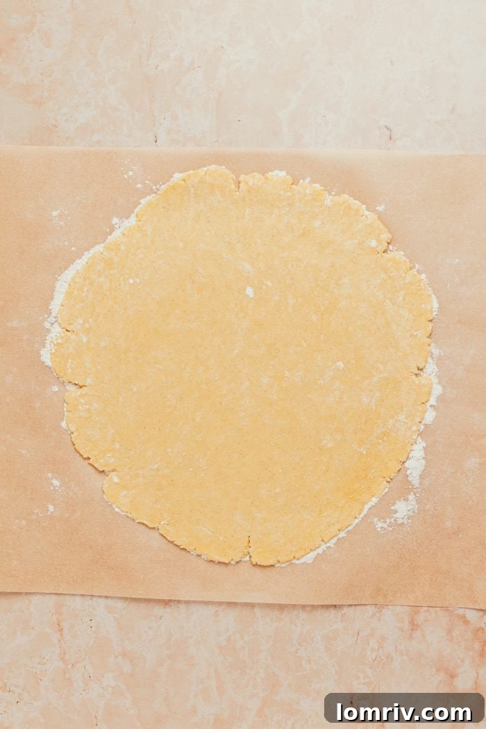 The tart shell dough, perfectly rolled out into a neat circle, resting on parchment paper.