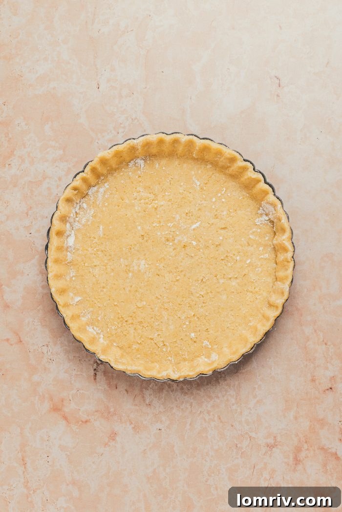 The unbaked tart shell dough meticulously pressed into the tart pan, showcasing its smooth surface.
