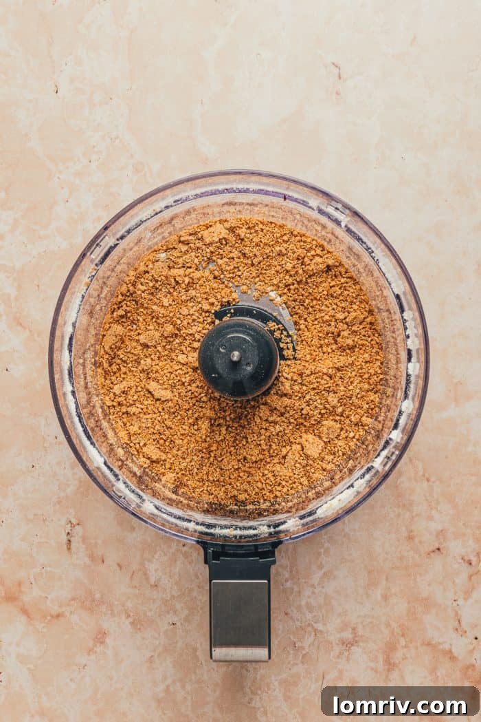 Finely ground roasted hazelnuts are pulsed in a food processor, resembling a coarse meal, ready for the frangipane.