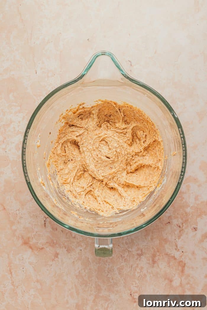The creamy, pale frangipane mixture, after being beaten with butter and sugar, fills a mixing bowl.