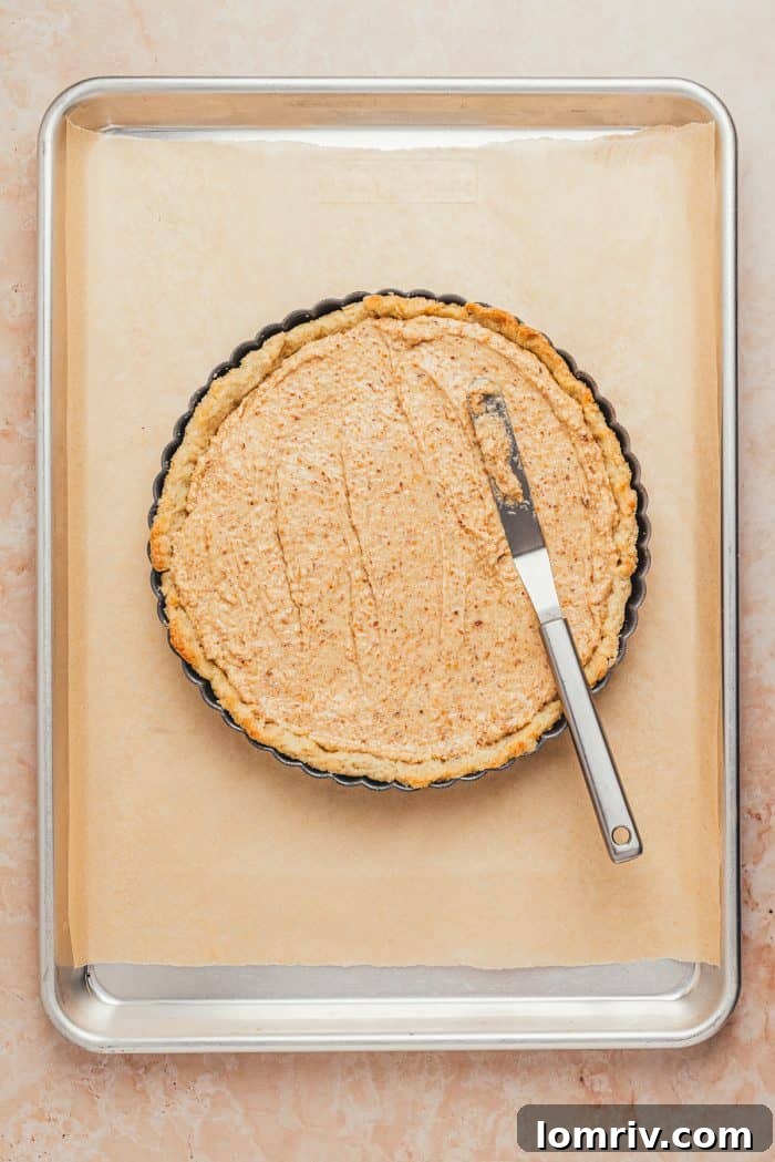The baked tart shell is seen with the hazelnut frangipane filling smoothly spread across its bottom in an even layer.