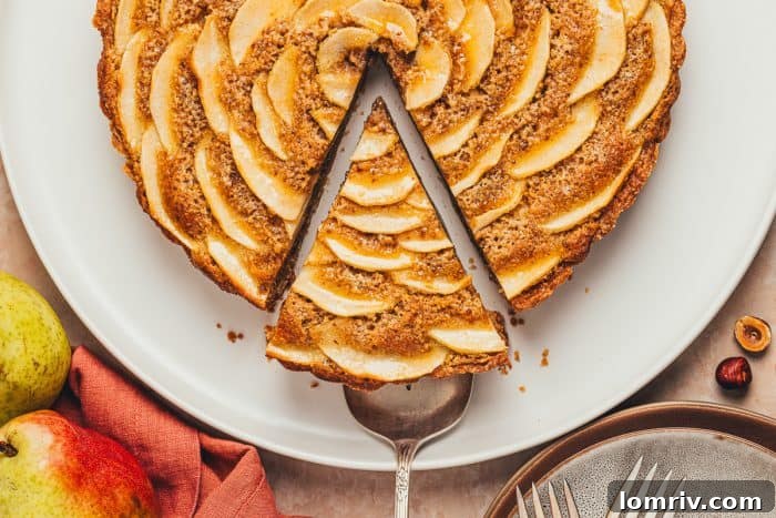 A tempting overhead shot of the pear frangipane tart with one slice carefully removed, revealing the delightful interior.