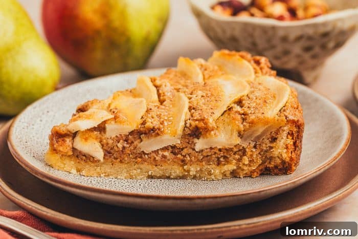 An inviting image of a slice of pear tart presented on two pristine white plates, with a soft focus on fresh pears in the background.