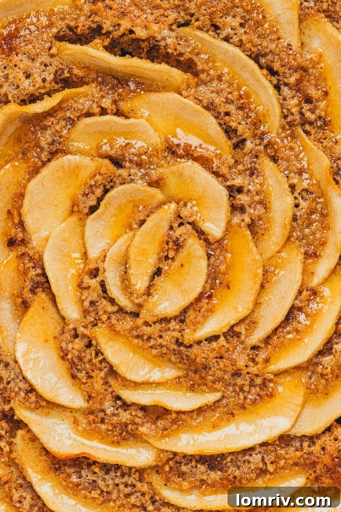 A detailed shot showcasing the beautiful texture of the frangipane filling, dotted with specks of ground hazelnuts, beneath the pear topping.