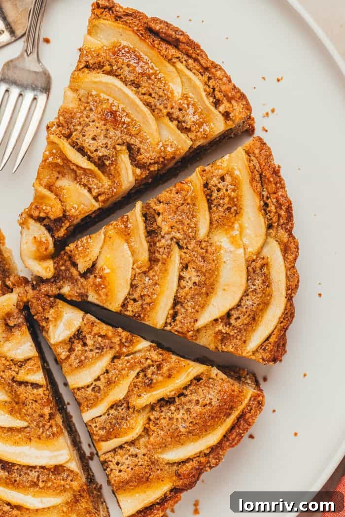 An overhead perspective of the baked pear frangipane tart, neatly sliced into wedges, ready to be served.
