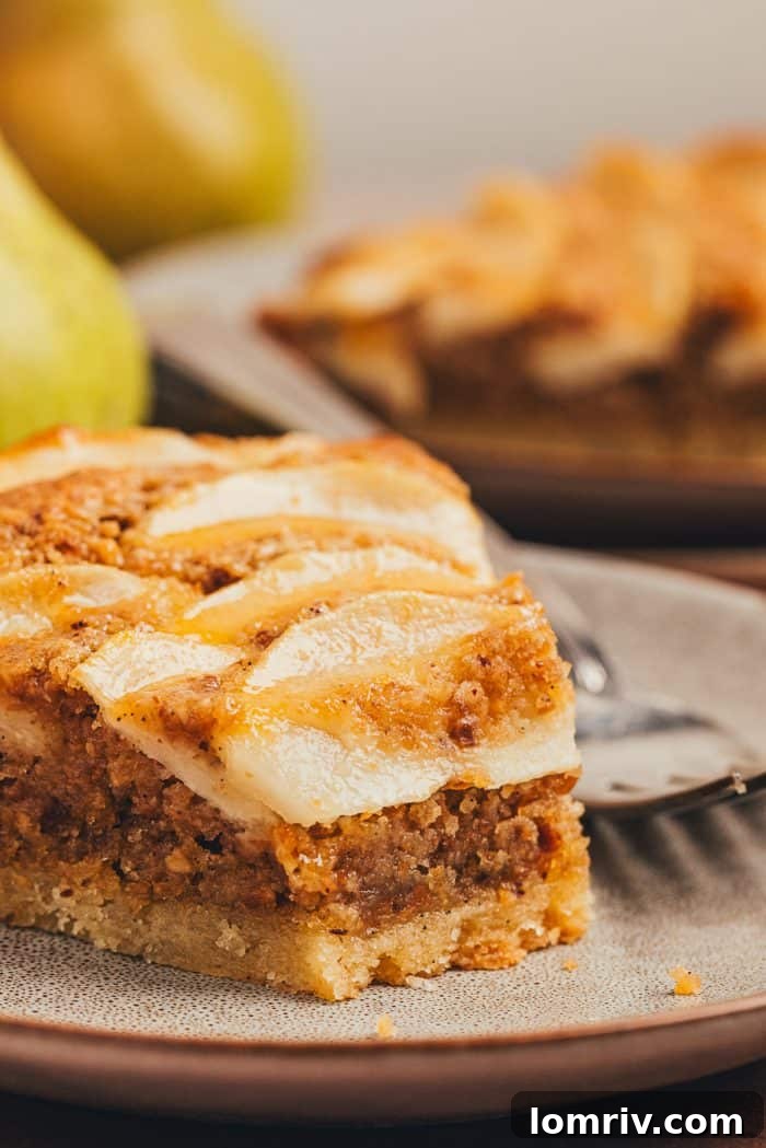 Another close-up of a delectable slice of pear frangipane tart on a plate, highlighting the delicious contrast of textures.