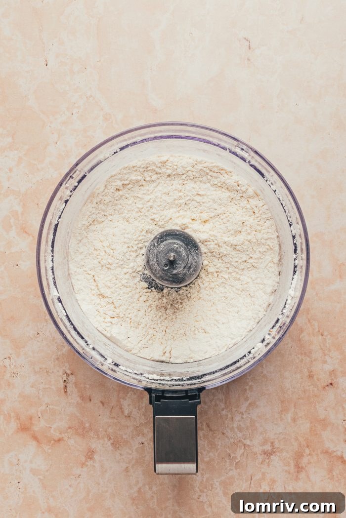 The dry ingredients for the tart shell—flour, sugar, and salt—are shown in a food processor bowl, ready for mixing.