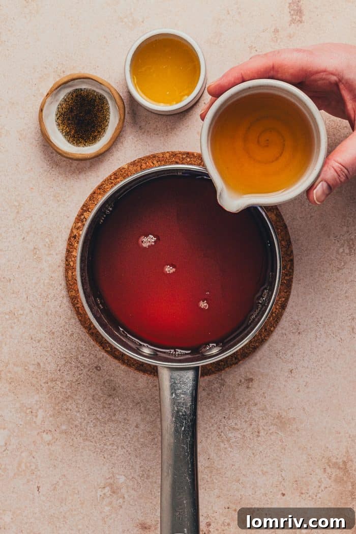 Fresh orange juice being added to the spiced chai mixture in a saucepan, contributing a bright, citrusy note.