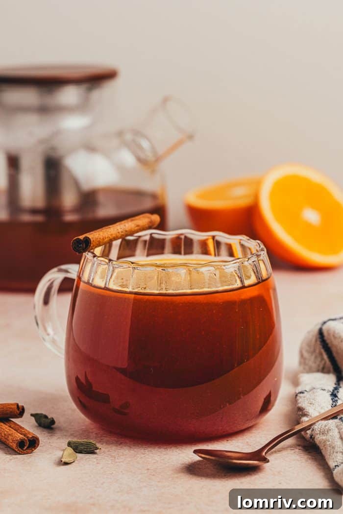 A perfectly garnished glass mug of chai vanilla bean hot toddy with orange slices and a cinnamon stick, ready to be served.