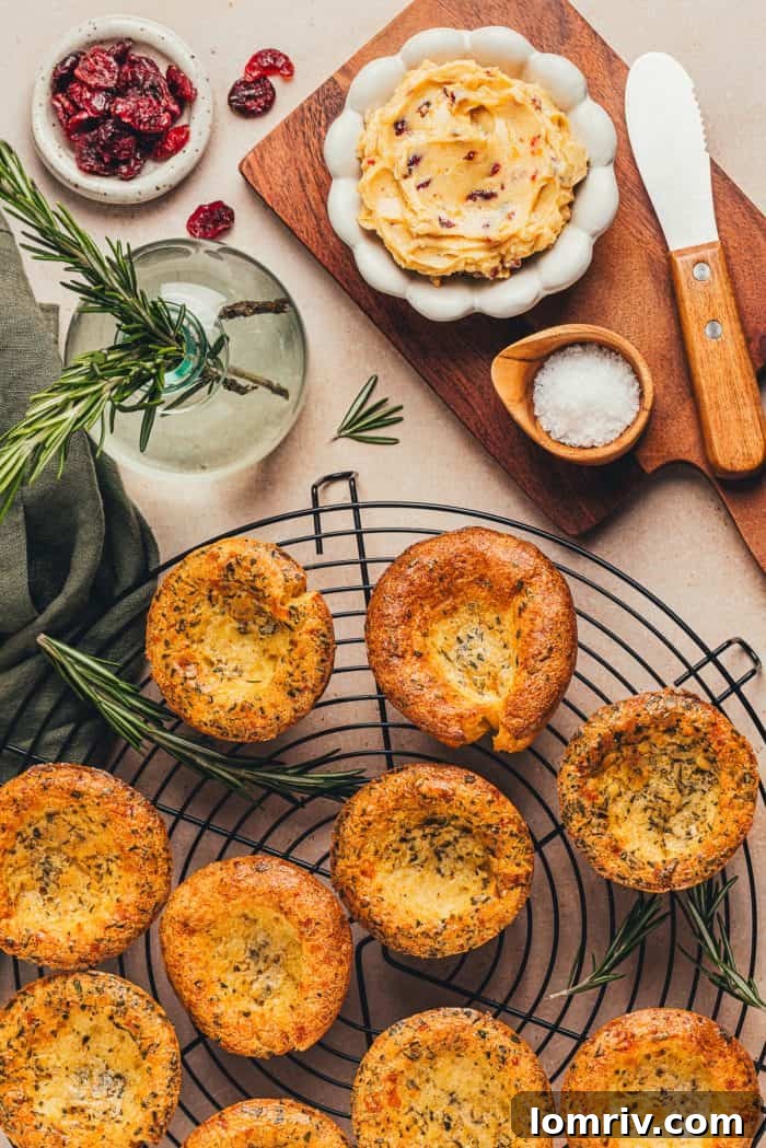 A few brown butter popovers on a cooling rack with a bowl of butter in the background.