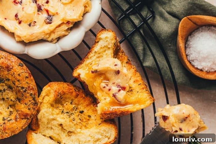 A few brown butter popovers on a cooling rack with a bowl of butter in the background.