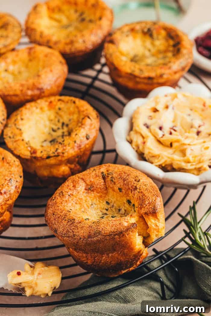 A few brown butter popovers on a cooling rack with a bowl of butter in the background.