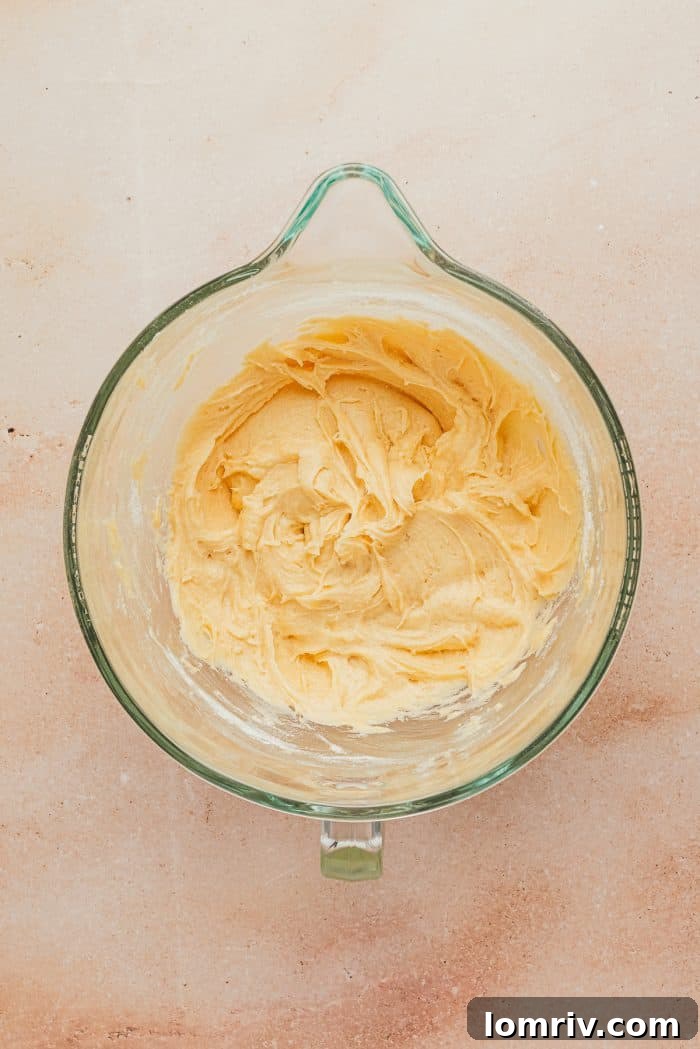 A glass mixing bowl with creamed butter and sugar, light and fluffy, prepared for the cake batter.