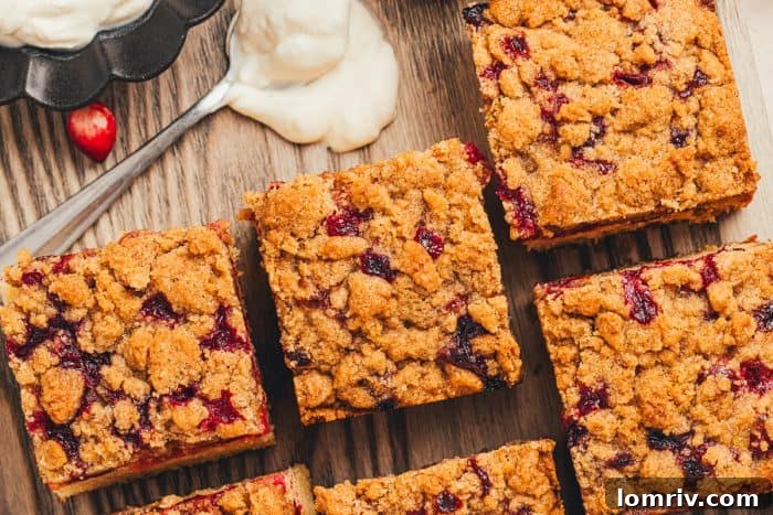 Several slices of homemade cranberry crumb cake, each with a perfectly golden and crisp streusel topping, arranged on a serving platter.