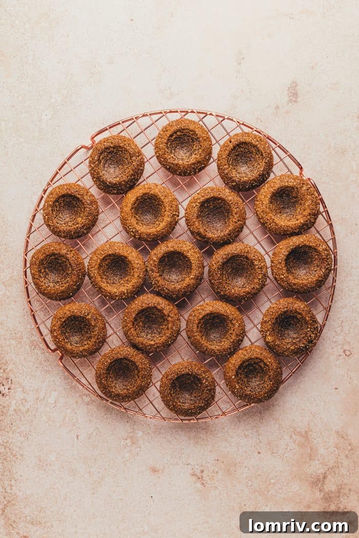 The baked gingerbread thumbprint cookies on a cooling rack.
