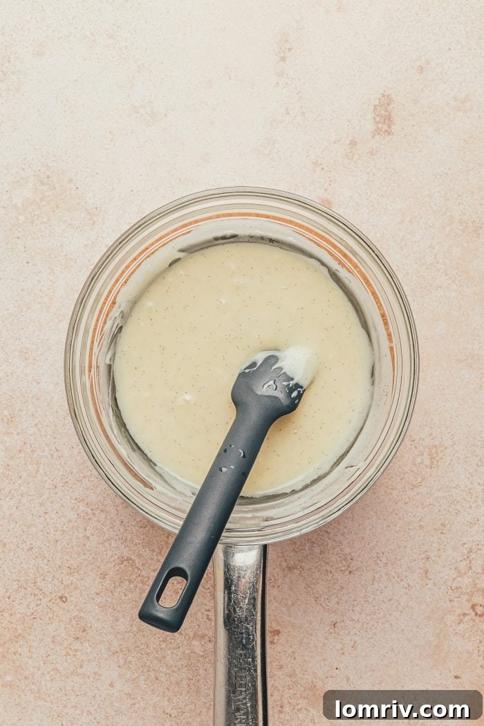 The melted white chocolate filling in a glass mixing bowl with a spatula.