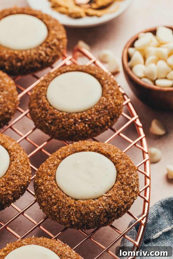 A variety of gingerbread thumbprint cookies on a cooling rack.