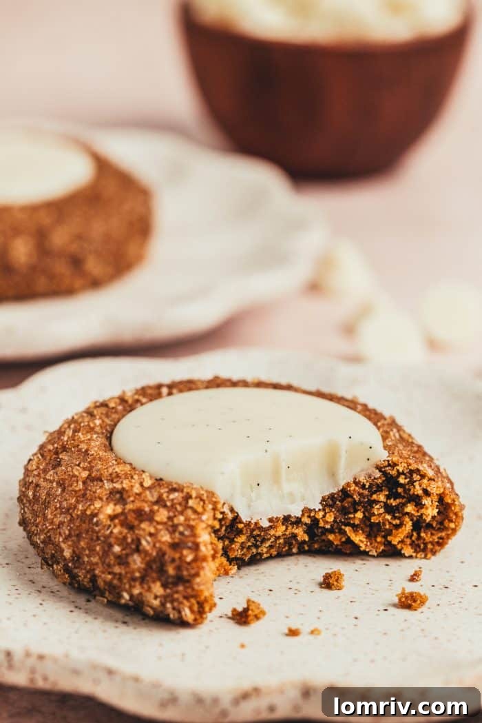 A plate with a thumbprint cookie on it with a bite taken out of it. 