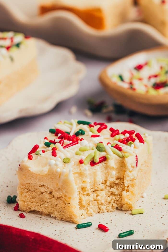 A sugar cookie bar with a bite taken out of it on a plate.