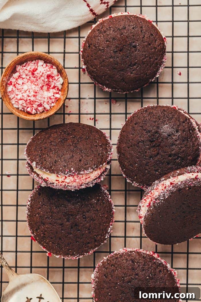 A collection of festive chocolate peppermint whoopie pies on a cooling rack, generously coated with crushed candy canes.