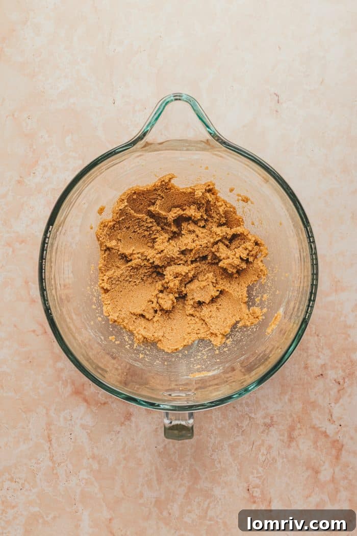 A clear glass mixing bowl containing perfectly creamed butter and light brown sugar, ready for the next step in whoopie pie preparation.