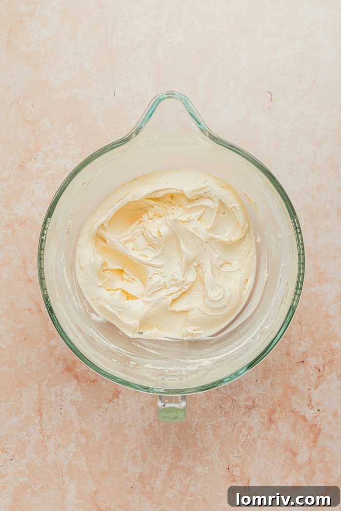 A pristine glass mixing bowl showcasing the creamy, dreamy white chocolate peppermint buttercream frosting, ready for piping.