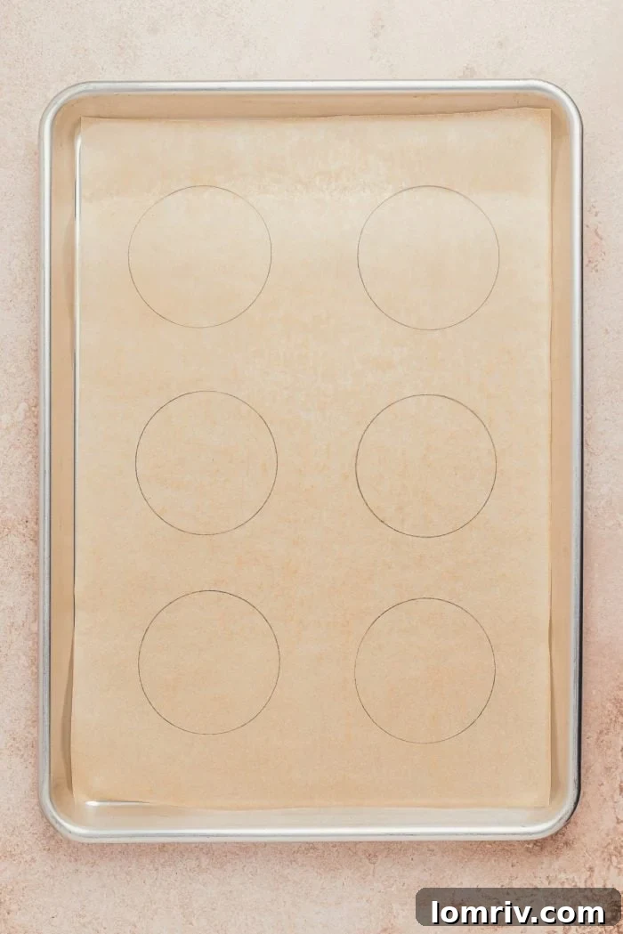 A baking pan lined with parchment paper, prepared for drawing circles to guide the pavlova formation.
