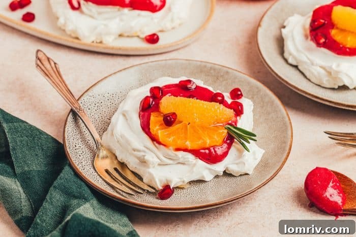 A single mini pavlova with cranberry curd, orange slices, and pomegranate arils on a plate, with a fork poised for a bite.
