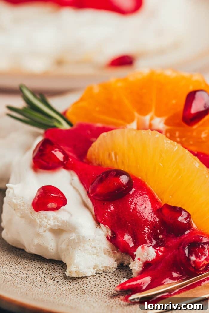 A mini pavlova beautifully presented with cranberry curd, orange slices, and a touch of rosemary, ready to serve.