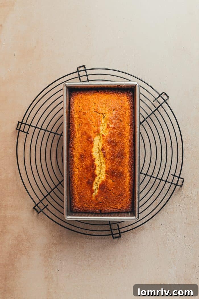 A freshly baked lemon Thyme pound cake rests on a wire cooling rack, allowing air to circulate around it.