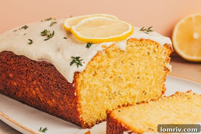 A lemon Thyme cake loaf, artfully cut into perfect slices, is elegantly presented on a white platter, inviting enjoyment.