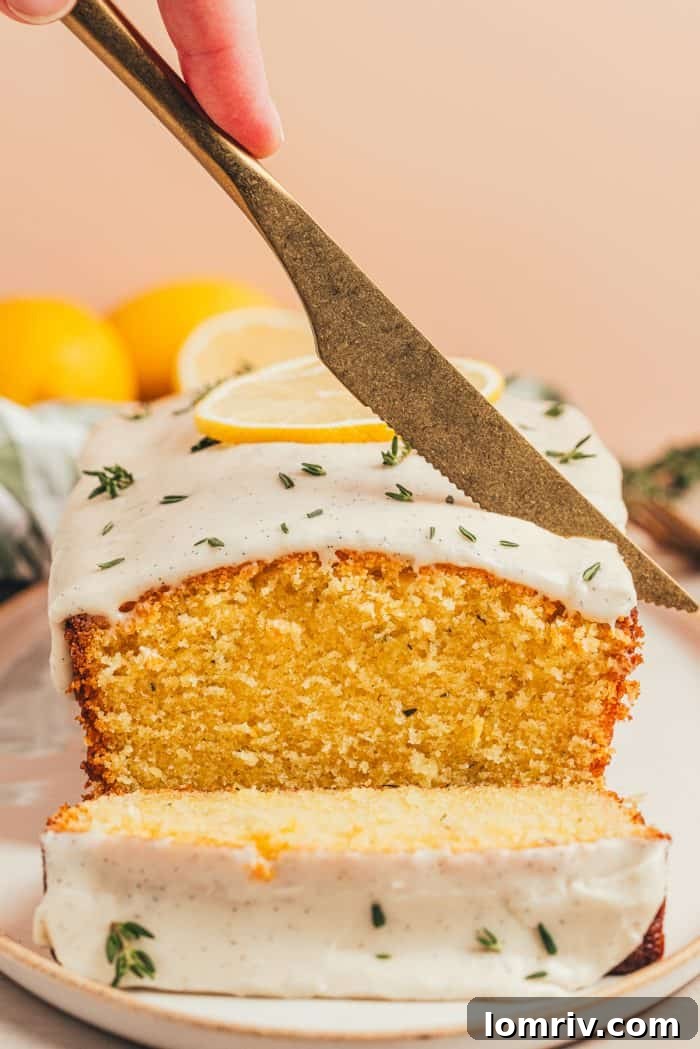 A close-up view of the lemon thyme loaf cake on a platter, featuring neatly cut slices and scattered fresh thyme sprigs, emphasizing its fresh, aromatic appeal.
