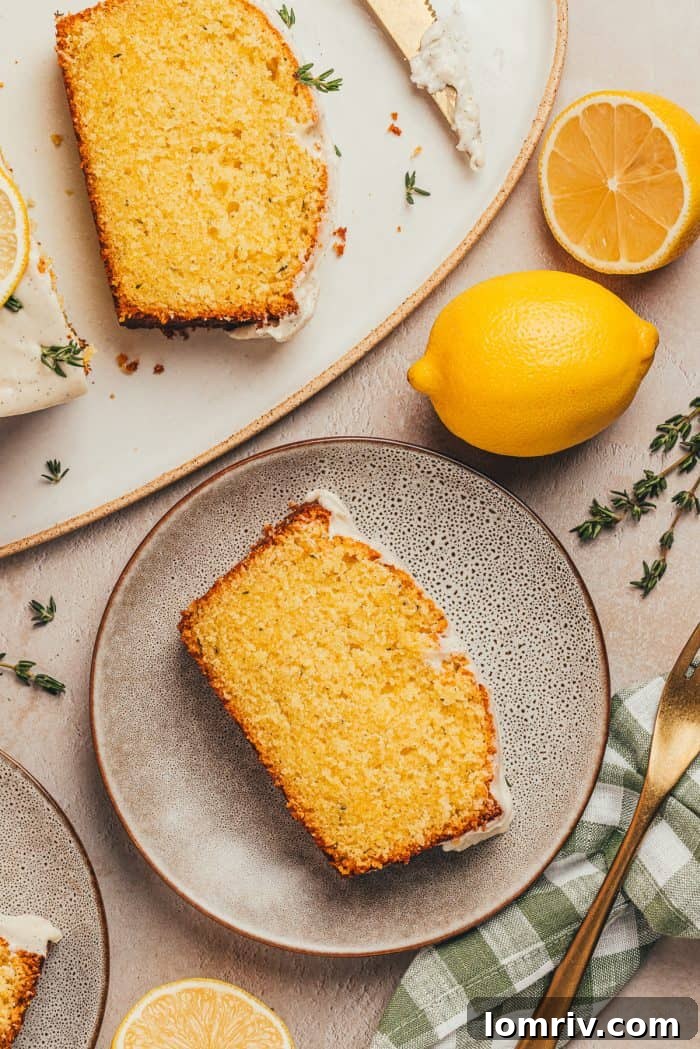 A delightful arrangement featuring a slice of lemon pound cake on a plate in the foreground, with the full lemon pound cake loaf and fresh lemons in the background.
