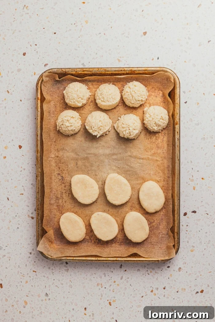 A mixture of the filling in a ball shape and some are in an egg shape on a tray with parchment paper.