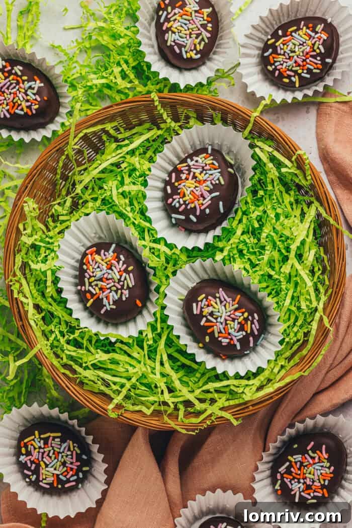 A few homemade chocolate-covered Easter eggs in confetti papers in a wicker basket with shredded green filling.