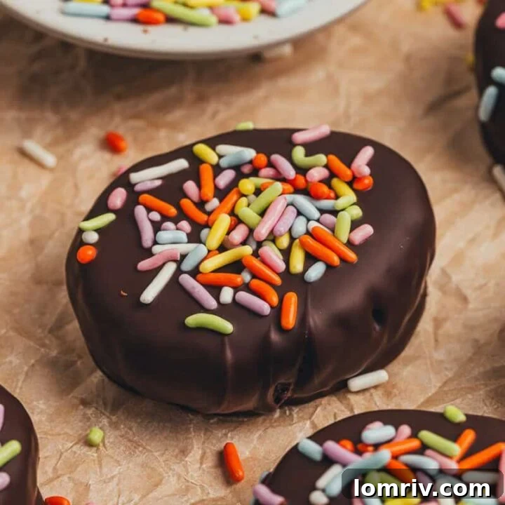 A few homemade chocolate Easter eggs scattered on parchment paper with a small plate filled with sprinkles.