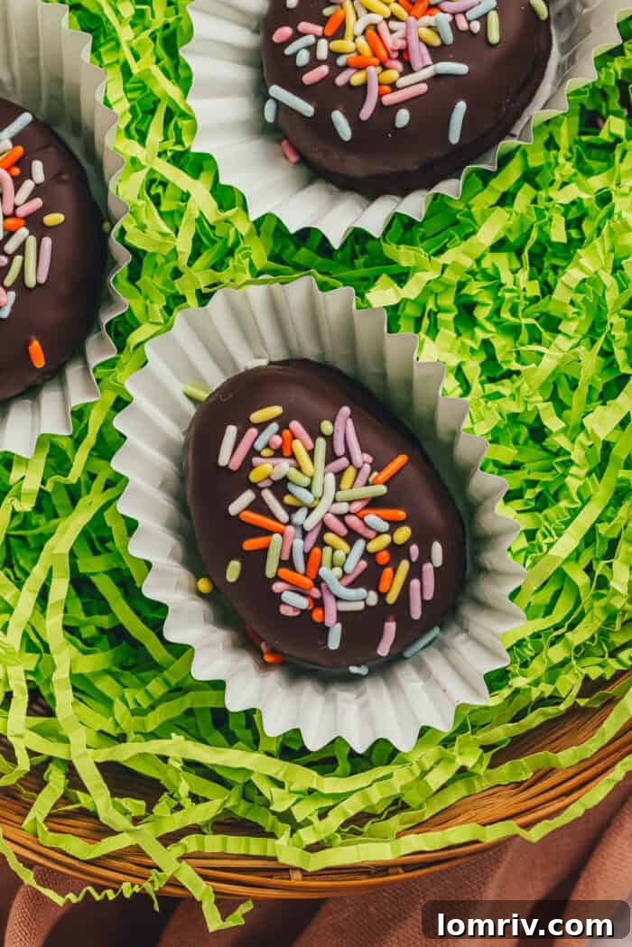 A few homemade chocolate-covered Easter eggs in confetti papers in a wicker basket with shredded green filling.