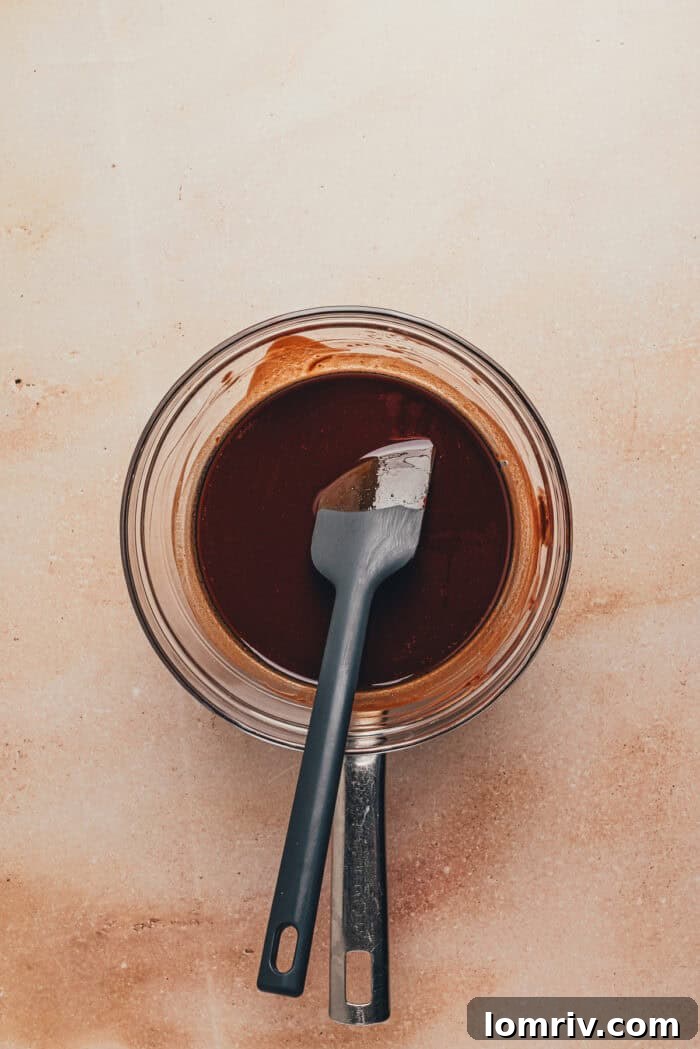 Melted semi-sweet chocolate and unsalted butter in a glass bowl, perfectly smooth and whisked to a homogenous consistency with a rubber spatula.