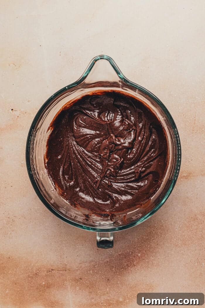 Half of the sifted dry ingredients have been added to the wet ingredients in a large glass mixing bowl, ready for the next mixing stage of the chocolate ricotta cake batter.