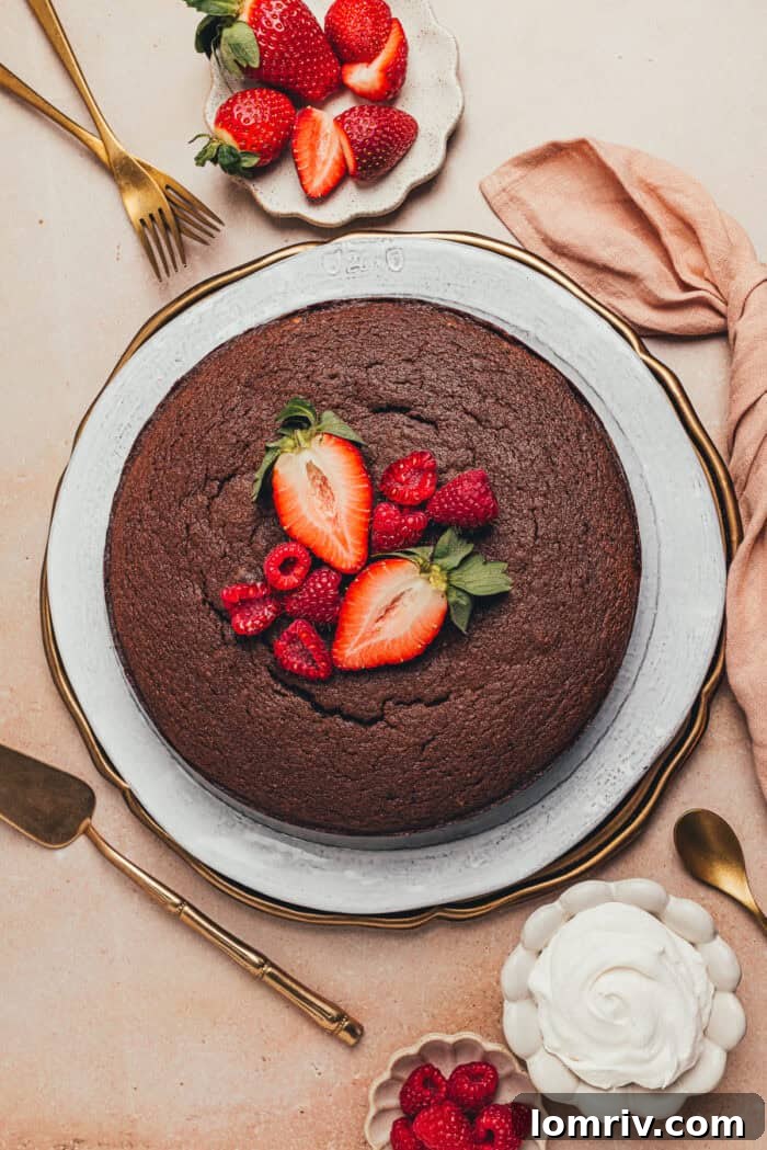 A beautifully presented chocolate ricotta cake, completely cooled and transferred to an elegant serving platter, adorned with a scattering of fresh fruit.