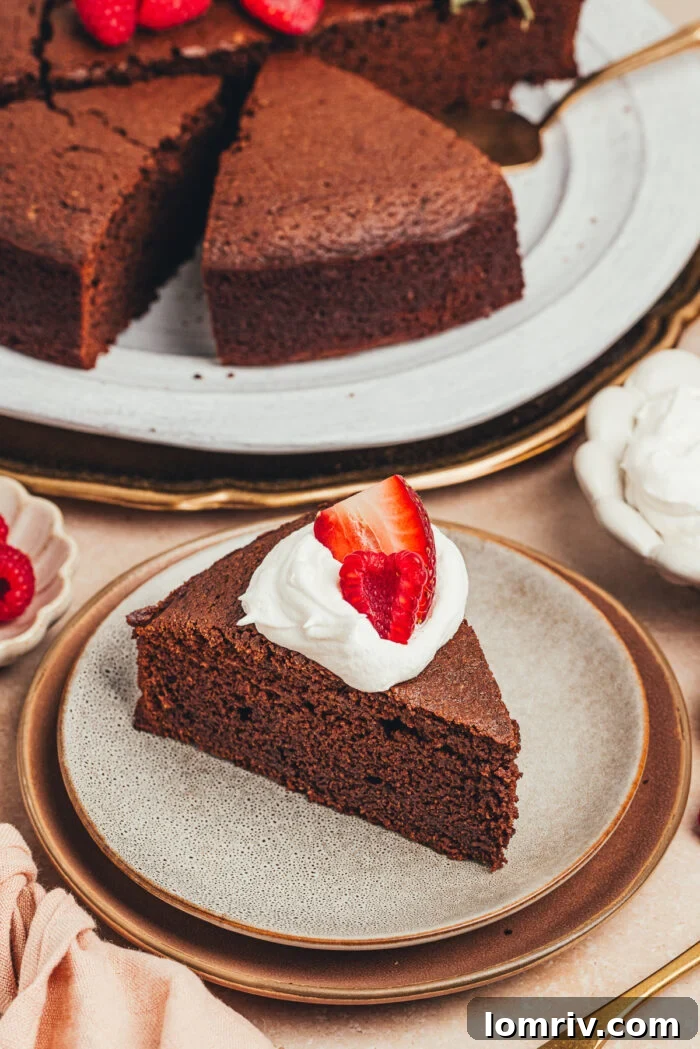 A delectable serving of homemade chocolate ricotta cake, adorned with fluffy whipped cream and a vibrant array of fresh berries, presented on a pristine white plate.