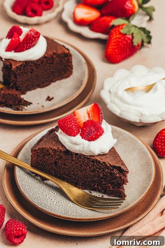 A close-up of a serving of chocolate ricotta cake topped with whipped cream and berries, highlighting the inviting texture of the cake.