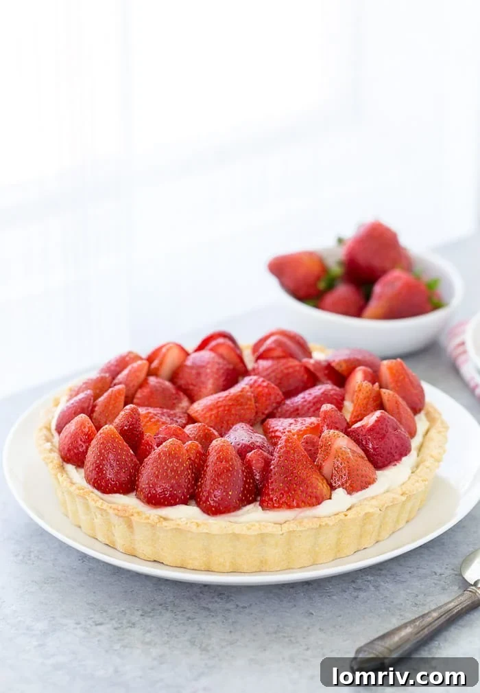 A stunning three-layered strawberry mascarpone tart featuring a golden, buttery crust, a luscious lemon mascarpone filling, and vibrant fresh strawberries on top.