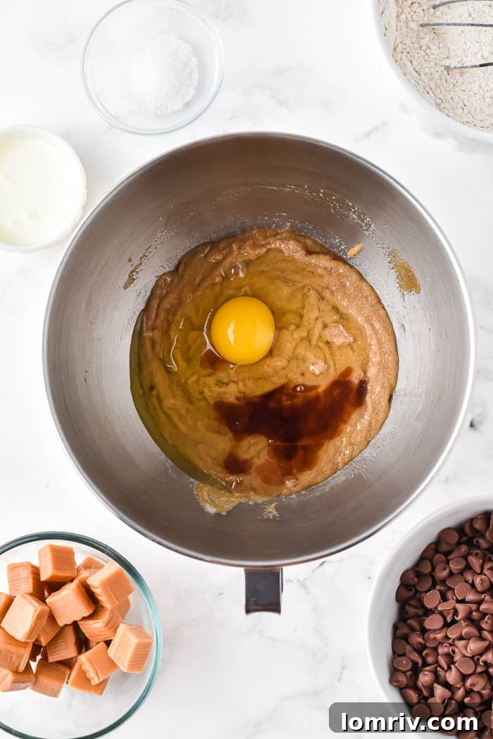 Adding eggs and vanilla to cookie dough mixture